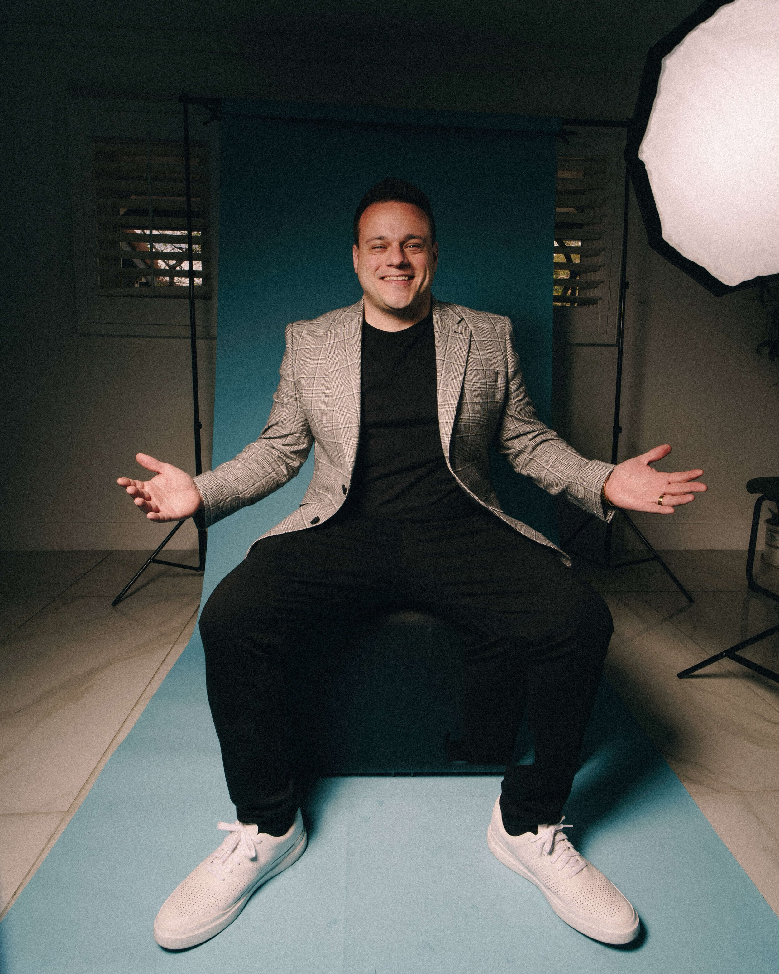 Portrait of DJ Nick Spinelli seated in front of a studio backdrop